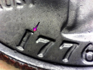 Microscopic view of an obverse die break error on a 1776-1976 Drummer Quarter, with arrows pointing to the raised metal crack on the date.