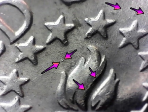 up close image of a bicentennial quarter with arrows noting die strike errors on the reverse of the coin between the stars and fire on the torch