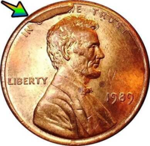 macro image of the obverse of a 1989 penny error displaying a large cud over the letters GOD