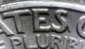 microscopic image of arrows noting where to look on the reverse of a 1964 quarter for the transitional error