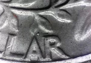 microscopic image of arrows noting where to look on the reverse of a 1964 quarter for the transitional errors